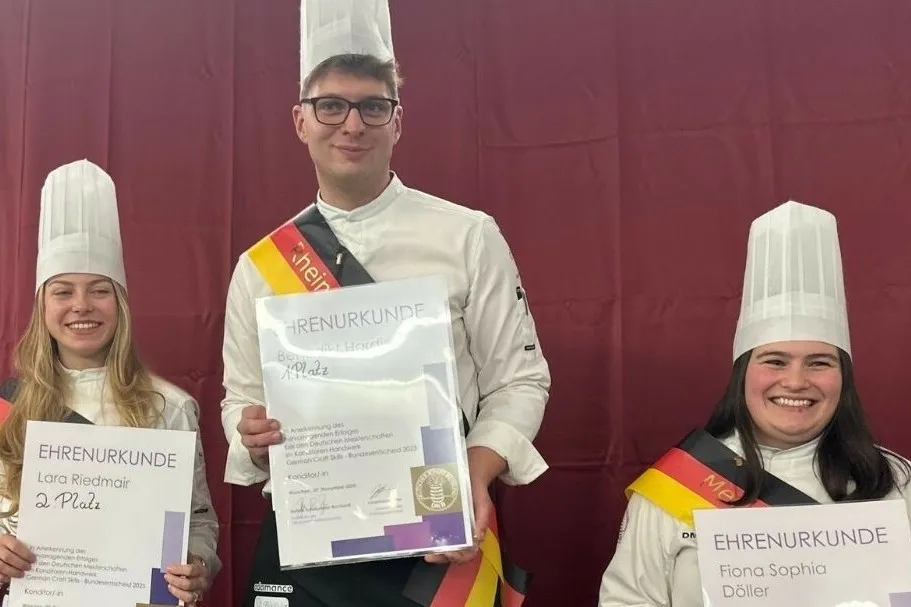 Lara Riedmair, Benedikt Hardieß und Fiona Sophia Döhler (v. l. n. r.) stehen nebeneinander, lächeln und halten ihre Urkunden in die Kamera.